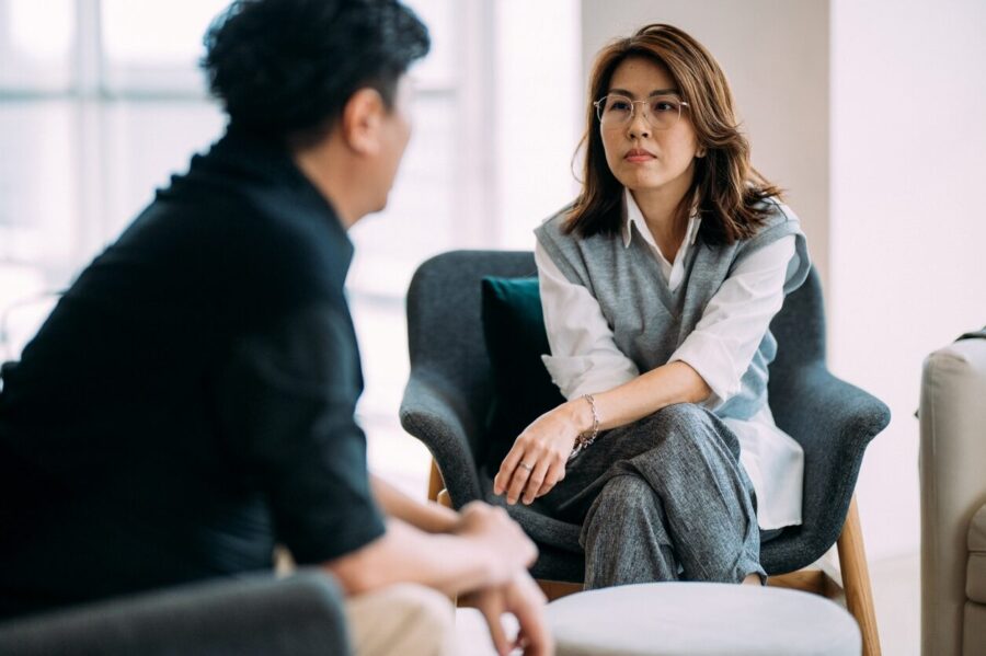 A female Asian therapist listening to her patient in office.